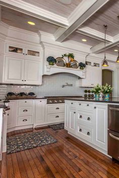 a large kitchen with white cabinets and wood flooring, along with an island in the middle