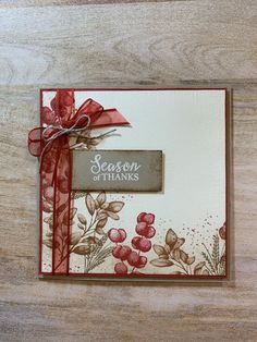 a handmade christmas card with red ribbon and floral designs on it, sitting on a wooden surface