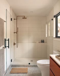 a bathroom with a shower, toilet and sink in it's center area next to a window