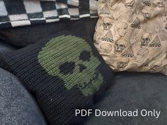 two knitted skull pillows sitting next to each other on top of a black couch