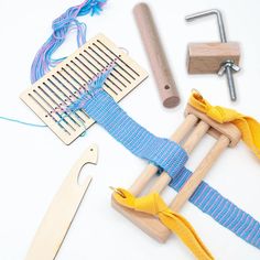 the tools needed to make a weaving project are laid out on a white surface with blue and yellow ribbons