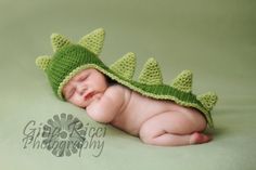 a baby wearing a green crocheted hat with a crocodile's head on it