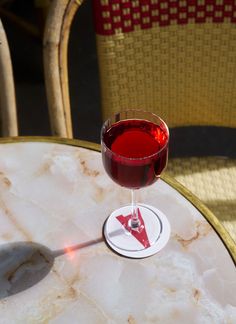 a glass of red wine sitting on top of a table