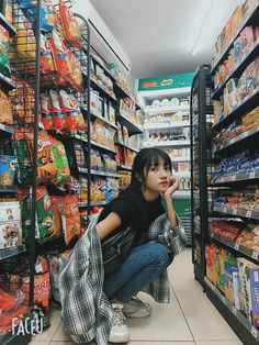 a woman squatting down in front of a grocery store aisle filled with food items