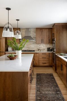 a large kitchen with wooden cabinets and white counter tops, along with a rug on the floor