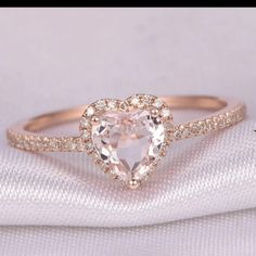 a heart shaped diamond ring on top of a white cloth