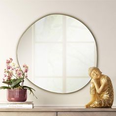 a mirror sitting on top of a dresser next to a vase with flowers in it