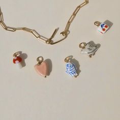 several charms are on a white surface next to a chain that is attached to it