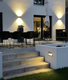 an outdoor dining area with steps leading to the back door and lights on either side