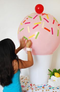 a woman is decorating a large balloon with sprinkles and a cherry