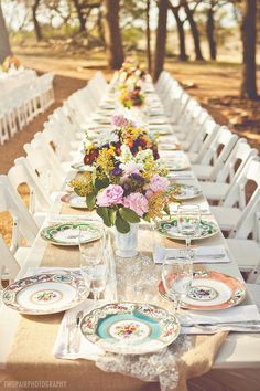 a long table with plates and flowers on it