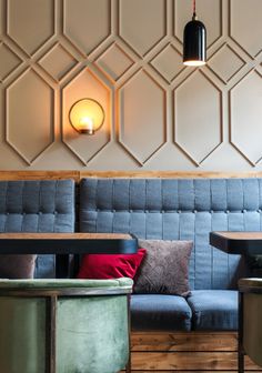 the interior of a restaurant with blue couches, tables and lamps on the wall