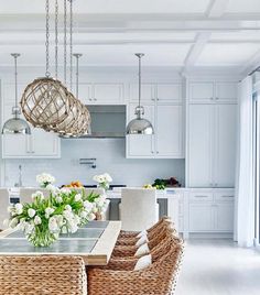 a dining room table and chairs with flowers in the center surrounded by wicker baskets