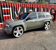 a silver suv parked in front of a red shipping container