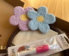 two crocheted flowers sitting on top of a table next to a tube of toothpaste