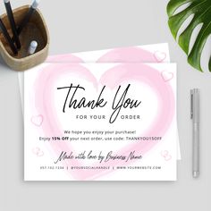 a thank card with a pink heart on it next to some pens and pencils