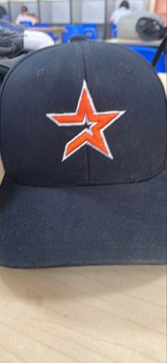 a baseball cap with an orange star on the front sitting on top of a table