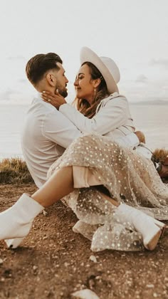 a man and woman sitting on the ground next to each other with their arms around each other