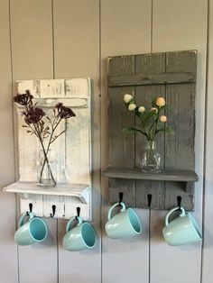 three vases with flowers in them are hanging on the wall next to some hooks