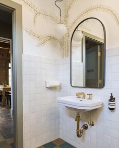 a white sink sitting under a bathroom mirror next to a wall mounted faucet