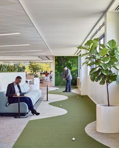 a man is sitting on a couch in an office with green carpet and white walls