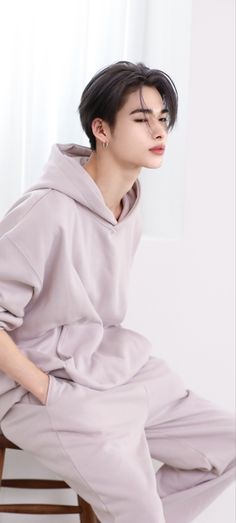 a person sitting on a stool with their eyes closed wearing a hoodie and sweatpants