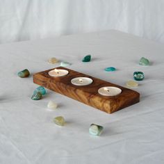 three tealight candles sitting on top of a wooden block surrounded by small pieces of glass