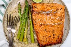 salmon, asparagus and rice on a plate with a side of lemon wedges