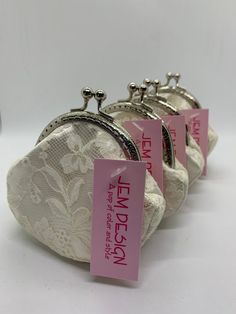 three white purses with pink tags on them sitting next to each other in front of a white background