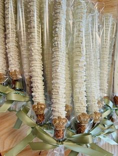 several white candles wrapped in plastic and tied with green ribbons on a wooden table top