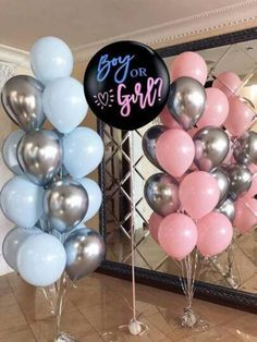 some balloons are on the ground and one is pink, silver and blue with a sign that says boy or girl