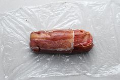 a piece of bacon wrapped in plastic sitting on top of a white tablecloth covered surface