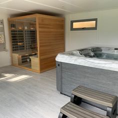 a large hot tub sitting in the middle of a room next to a wooden bench