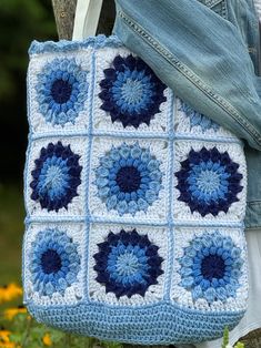 a blue and white crocheted bag is held by a woman's legs