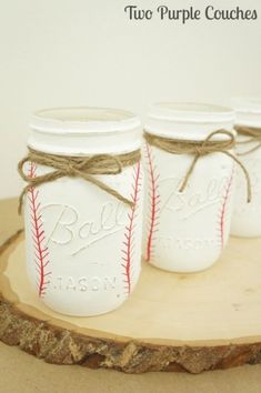 three mason jars with baseballs painted on them are sitting on a piece of wood