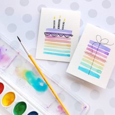 two cards with birthday candles on them next to watercolor paints