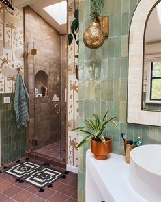 a bathroom with tiled walls and flooring has a plant on the counter next to the shower