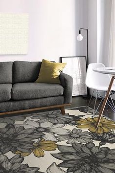 a living room with a gray couch and yellow flowers on the rug in front of it