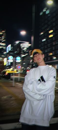 a man standing in front of a city street at night with his arms folded out