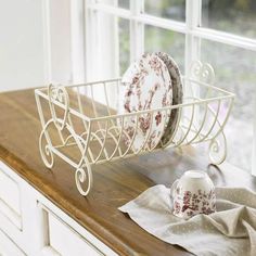 a kitchen counter with plates and cups in a wire basket on top of the counter