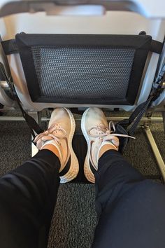 someone's feet are standing on an airplane seat with their shoes propped up in the back