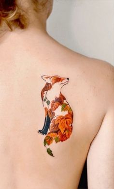 the back of a woman's shoulder with a tattoo of a fox and leaves on it