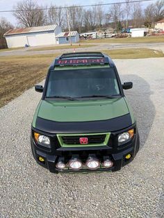 a green truck parked on top of a gravel road