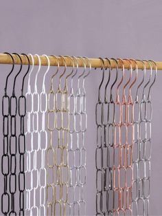 an assortment of metal clothes hangers on a wooden rail against a purple wall,