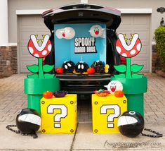 the trunk of a car decorated to look like mario kart is parked in front of a garage