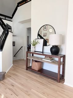 there is a table with a lamp on it in the living room next to stairs