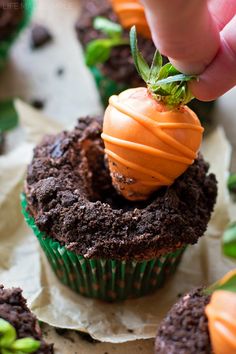 someone is picking up some carrots on top of cupcakes