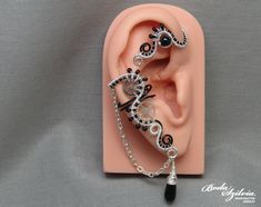 Steampunk ear wrap in silver and black color, decorated with black onyx. No piercing required! It's made of black artistic and nickel free silver plated wire, silver plated chain, seed beads, a black onyx gemstone, a matching black glass drop shaped bead and recycled stainless steel watch wheels. Available: - left ear - right ear  - pair Made for order. I'll need 1-5 days to make your ear cuff. Please note that each one is made 100% by hand and may vary a little from the photo. You can find more Handmade Black Ear Cuff Gift, Handmade Black Ear Cuff As Gift, Handmade Black Ear Cuff For Gift, Black Steampunk, Felt Pouch, Wrap Earrings, Steampunk Jewelry, Cuff Earrings, Black Glass