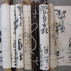 several old chinese writing on white paper tied to wooden sticks