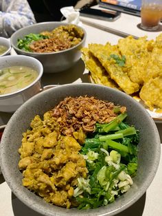 a bowl filled with different types of food on top of a table next to bowls of soup